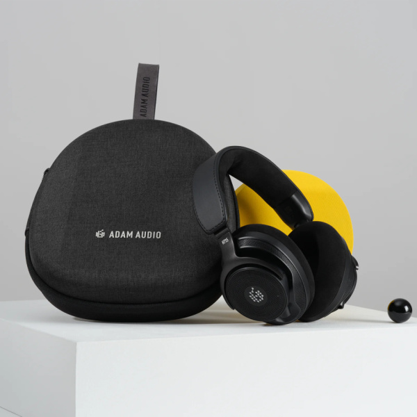 Auriculares H715 Reference con almohadillas de tela junto a su estuche rígido negro con logotipo ADAM Audio.